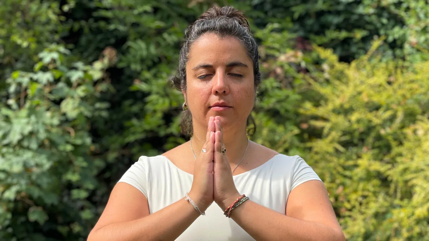 Maria Montserrat in namaste, eyes closed in a moment of quiet